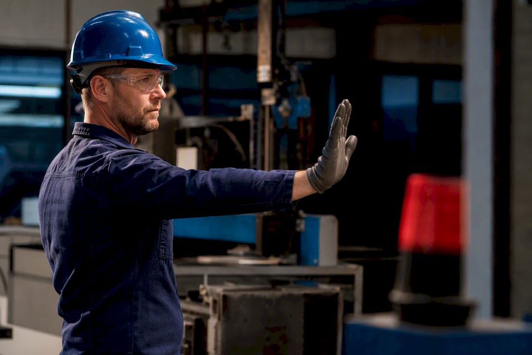 Worker giving hand signal near alarm
