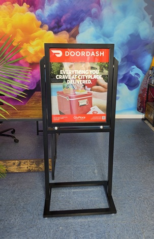 DoorDash ad on a black stand with a red header and food delivery image indoors.