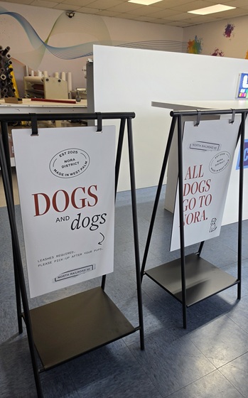 Two black display stands with white posters promoting dogs in an indoor space.